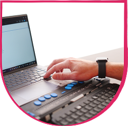 Hand using a braille display connected to a laptop keyboard