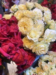 A vibrant display of fresh roses with red and pale yellow blooms. The flowers are tightly clustered, creating a rich, romantic atmosphere.