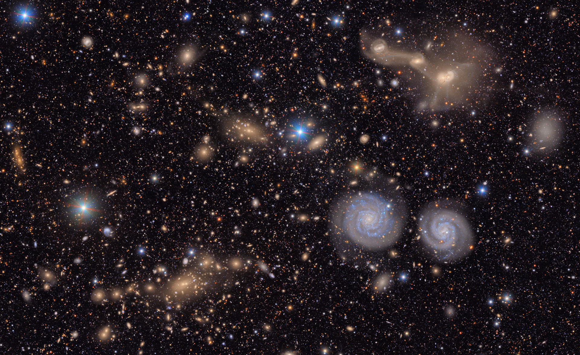 Space image filled with glowing blue, white and orange stars and galaxies.