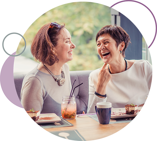 Two woman laughing over coffee after a credit card purchase.